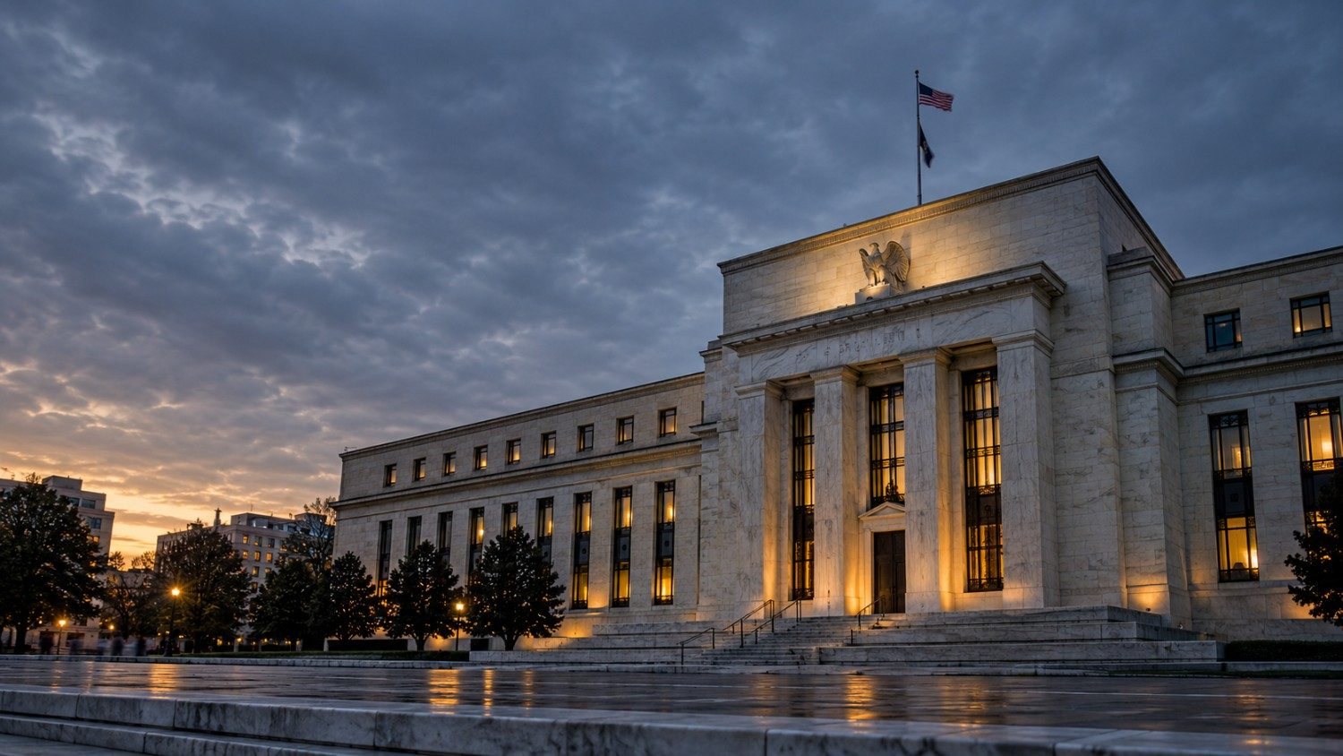 The Federal Reserve building in Washington, D.C. at dusk, illuminated against a dramatic cloudy sky, days before its September 15-16 interest rate decision that markets are watching closely for gold price direction.