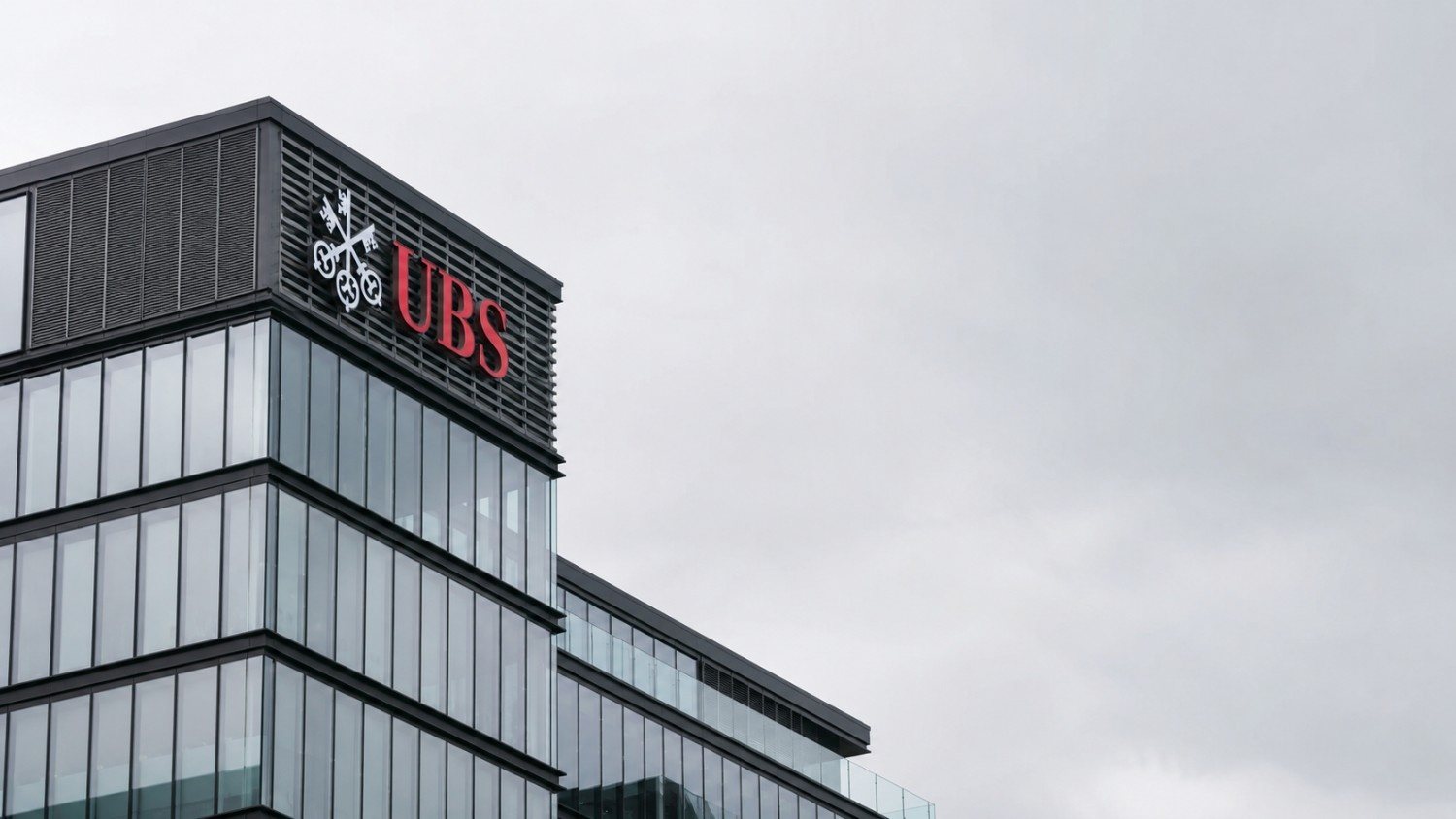 UBS headquarters building exterior with UBS gold price target revision — glass and steel corporate architecture under overcast sky